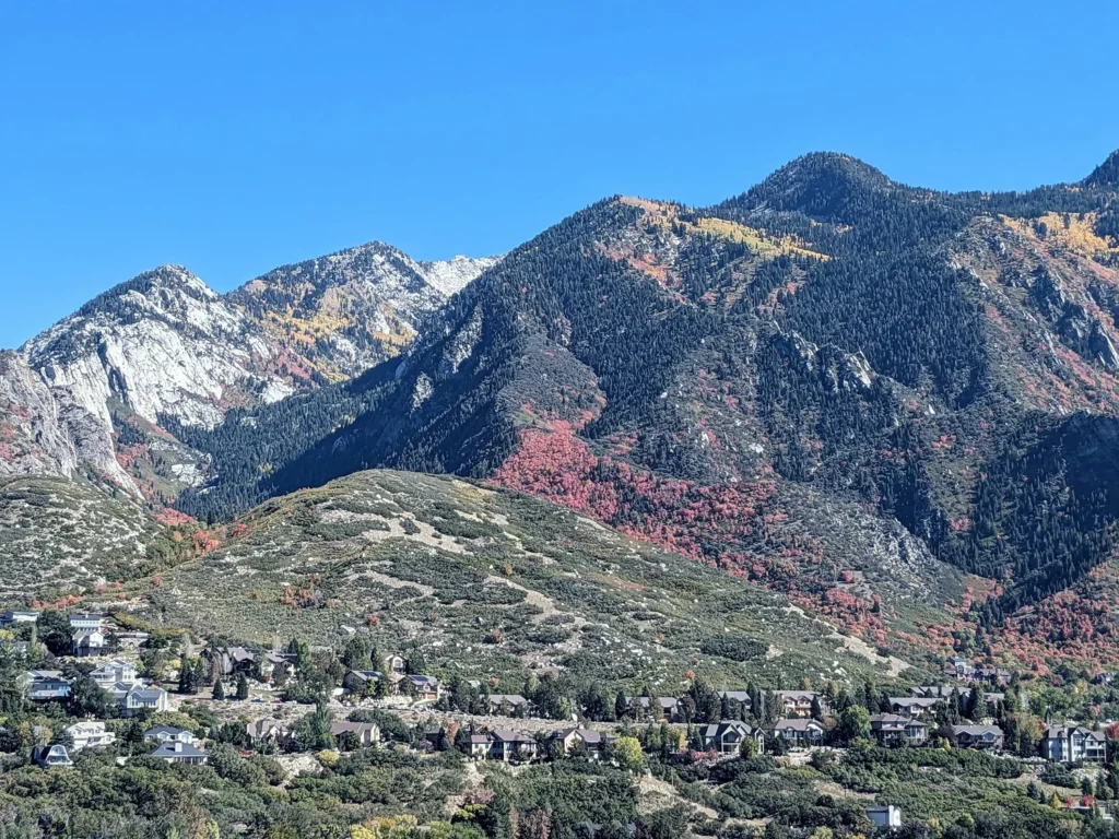 Mountain landscape with autumn foliage and residential homes under clear blue sky